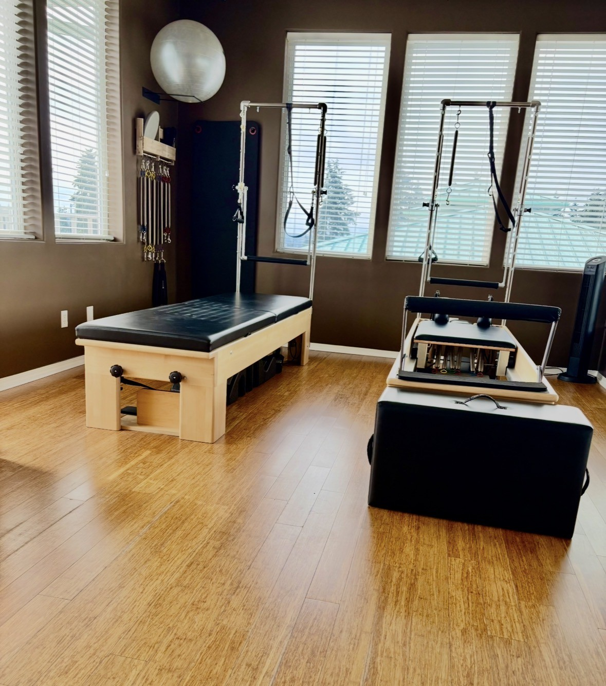 Trapeze table and reformer beside sunlit windows in the studio